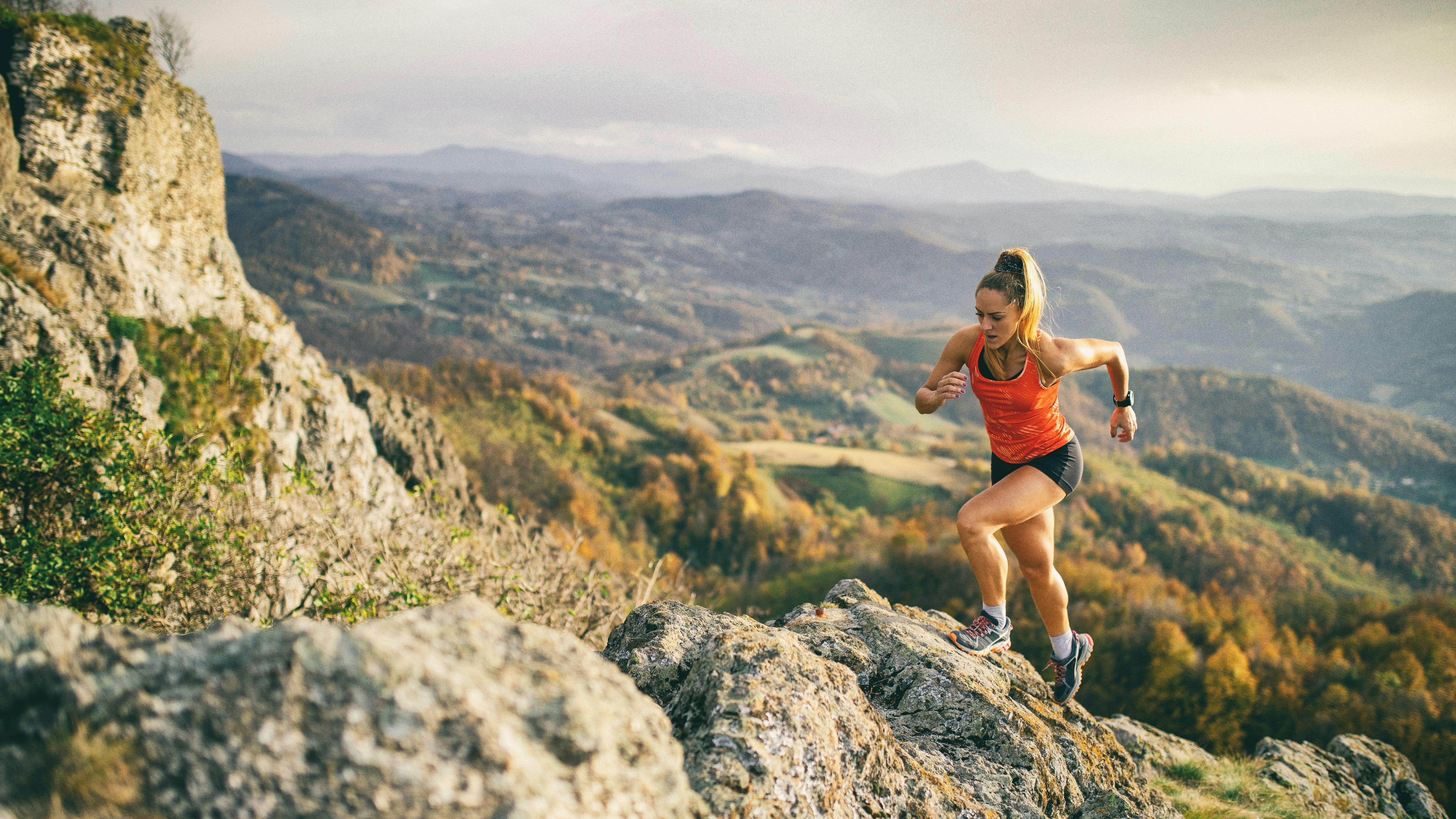 Mujer joven corriendo en sendero de montaña