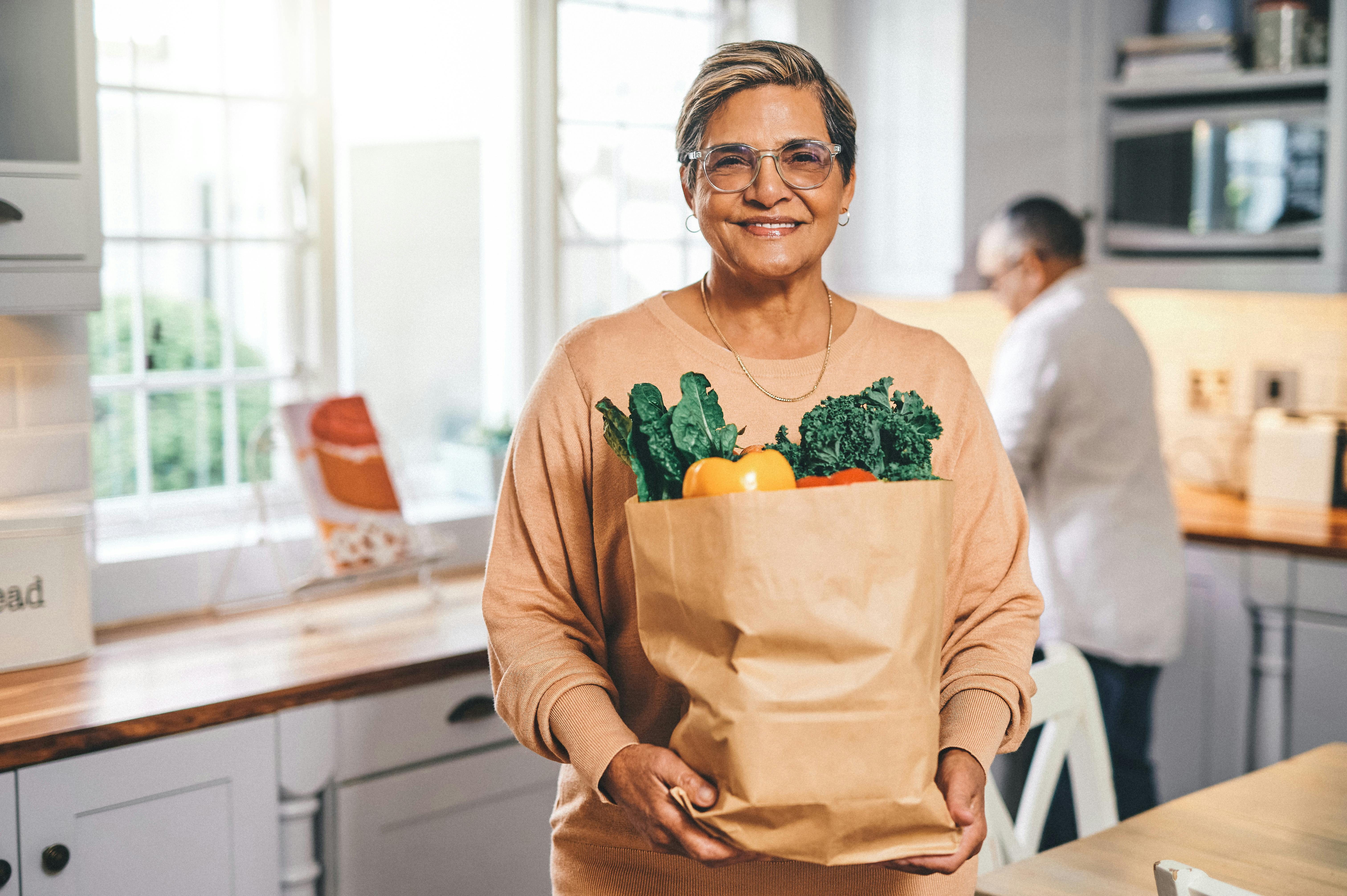 Shot of a elderly woman holding a grocery bag in the kitchen